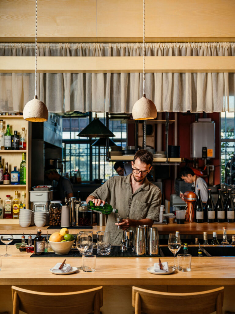 Robin Corbett preparing cocktails behind the bar by Johnny C.Y. Lam

